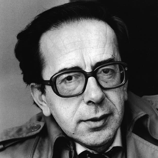 A black-and-white portrait of Ismail Kadare. He wears dark-rimmed glasses.